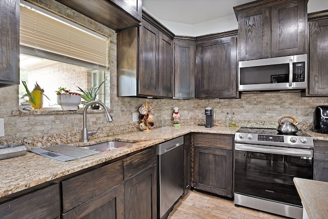 kitchen featuring light wood-type flooring, light stone countertops, stainless steel appliances, and backsplash