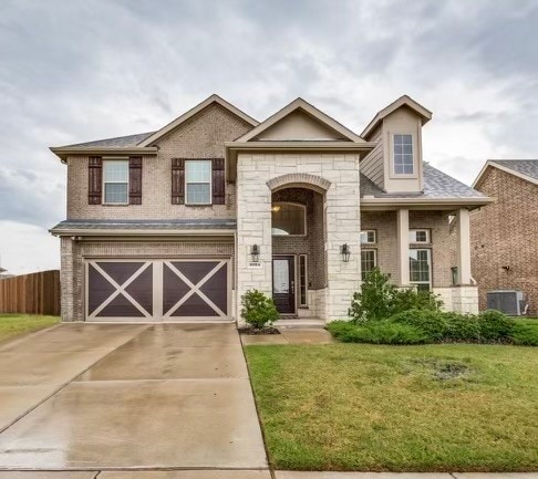 view of front of home with central AC, a garage, and a front lawn