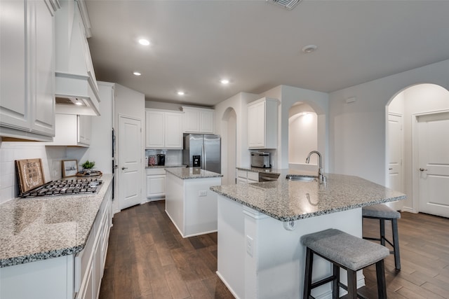 kitchen with a kitchen island with sink, dark hardwood / wood-style flooring, sink, appliances with stainless steel finishes, and white cabinets