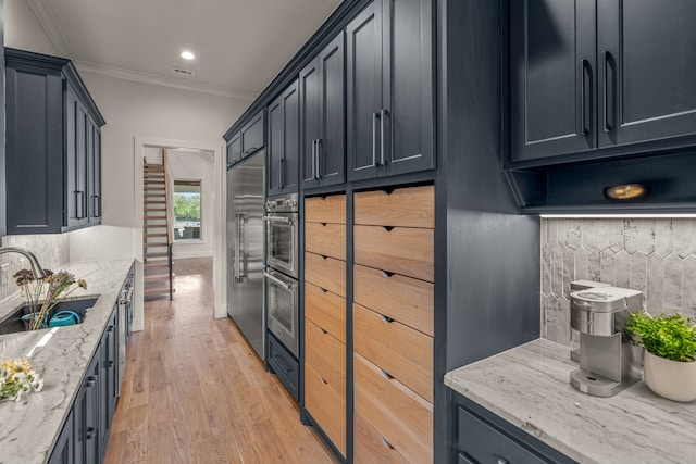 kitchen featuring light hardwood / wood-style flooring, light stone counters, sink, built in refrigerator, and ornamental molding