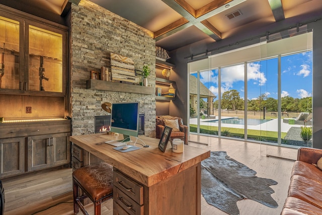 office space featuring coffered ceiling, beamed ceiling, light wood-type flooring, and a fireplace