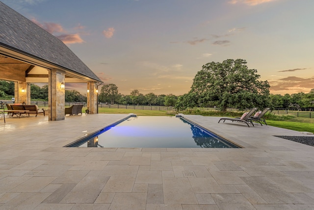 pool at dusk featuring a patio