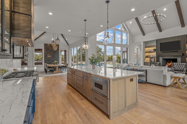 kitchen with a fireplace, beamed ceiling, high vaulted ceiling, light hardwood / wood-style flooring, and appliances with stainless steel finishes