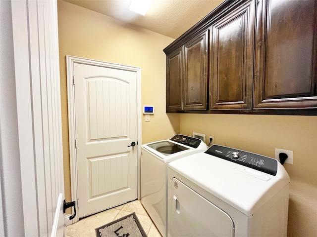 washroom with light tile patterned floors, independent washer and dryer, cabinets, and a textured ceiling