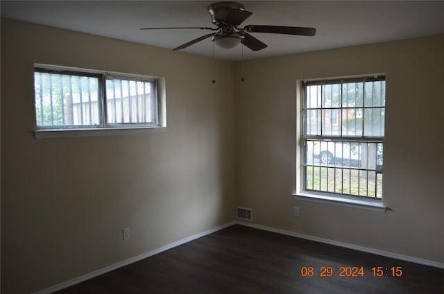 spare room featuring visible vents, baseboards, dark wood finished floors, and a ceiling fan