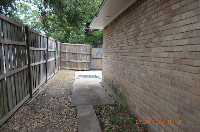 view of side of home with brick siding and fence