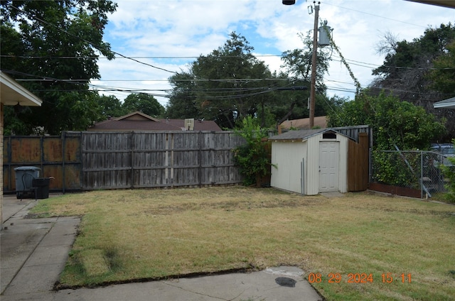 view of yard featuring an outbuilding, a storage shed, and a fenced backyard