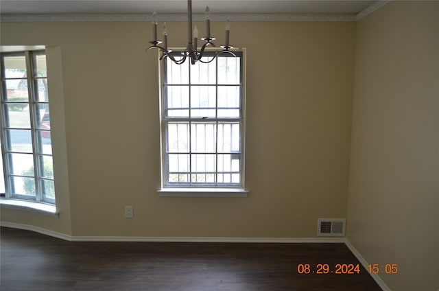 unfurnished dining area with ornamental molding, plenty of natural light, an inviting chandelier, and dark hardwood / wood-style flooring