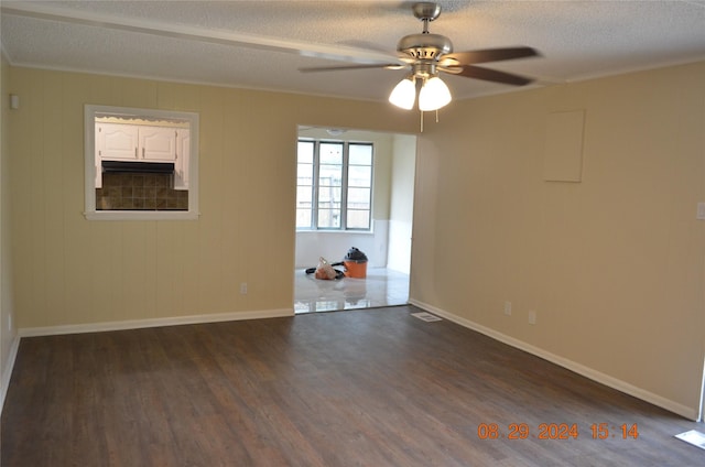 spare room with a ceiling fan, baseboards, dark wood finished floors, ornamental molding, and a textured ceiling