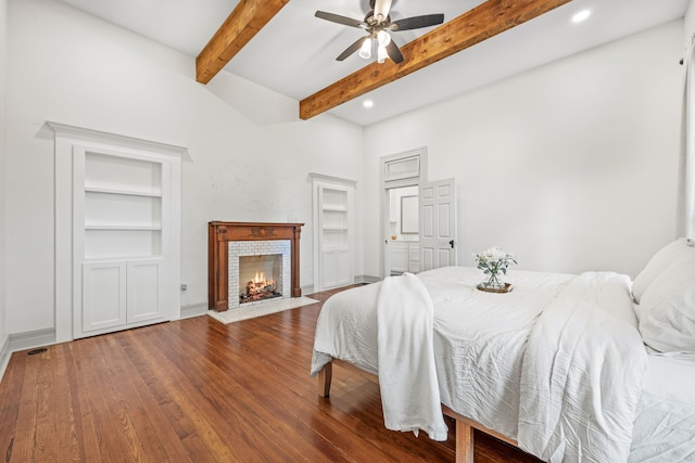 bedroom with wood-type flooring, beam ceiling, a fireplace, a towering ceiling, and ceiling fan