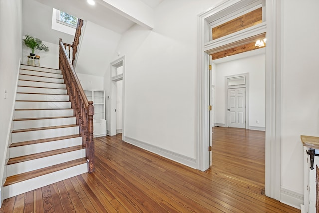 stairway with wood-type flooring, a skylight, and a high ceiling