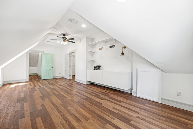 additional living space featuring built in shelves, lofted ceiling, dark hardwood / wood-style flooring, and ceiling fan