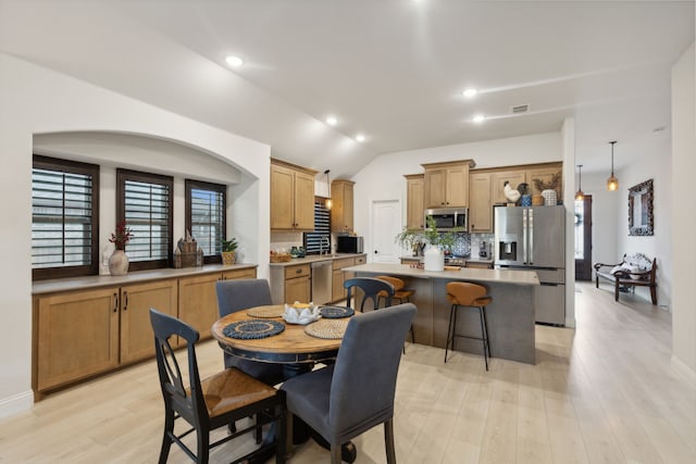 dining area featuring vaulted ceiling and light wood-type flooring