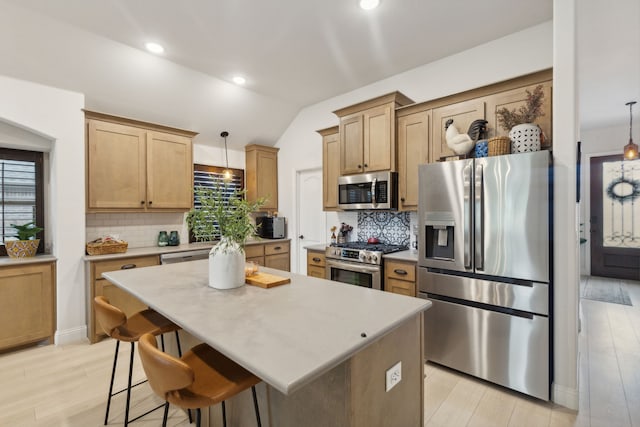 kitchen featuring vaulted ceiling, stainless steel appliances, tasteful backsplash, and light wood-style flooring