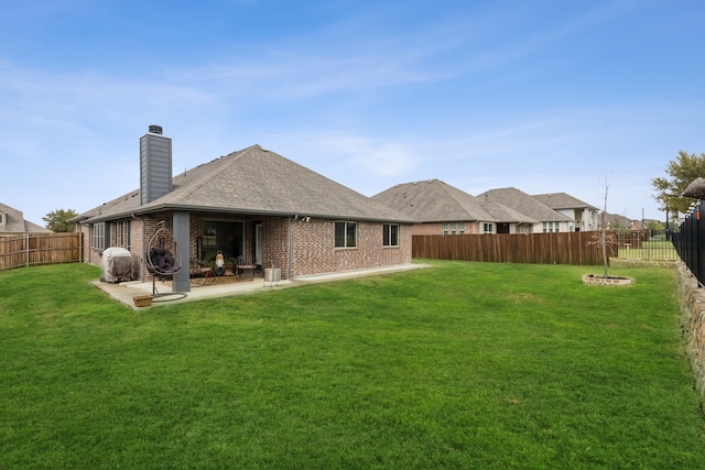 rear view of house featuring a yard, brick siding, and a fenced backyard