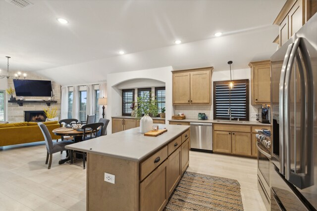 kitchen with pendant lighting, a stone fireplace, stainless steel appliances, and a kitchen island