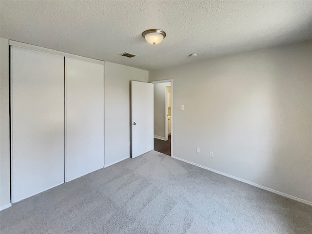 unfurnished bedroom with a textured ceiling, carpet flooring, and a closet