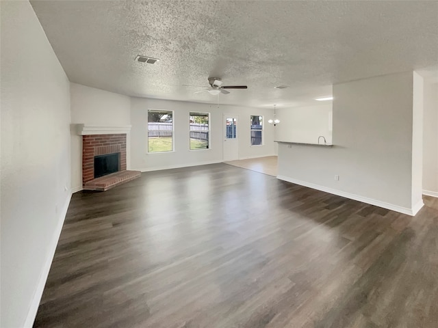 unfurnished living room with a fireplace, dark wood-type flooring, a textured ceiling, and ceiling fan