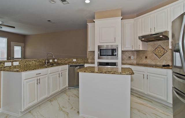 kitchen with a center island, stainless steel appliances, sink, dark stone counters, and ceiling fan