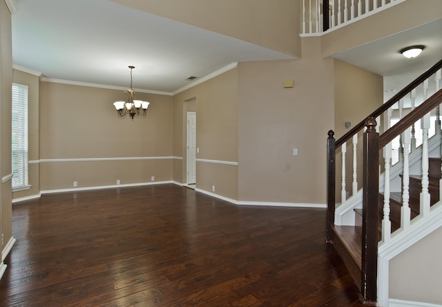 spare room featuring dark hardwood / wood-style floors, an inviting chandelier, and crown molding