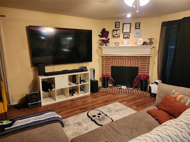 living room featuring a textured ceiling, hardwood / wood-style floors, and a brick fireplace