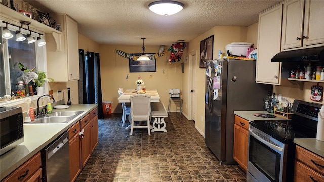 kitchen with hanging light fixtures, stainless steel appliances, a textured ceiling, and sink