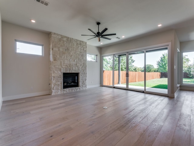 unfurnished living room with light hardwood / wood-style flooring, a healthy amount of sunlight, a fireplace, and ceiling fan