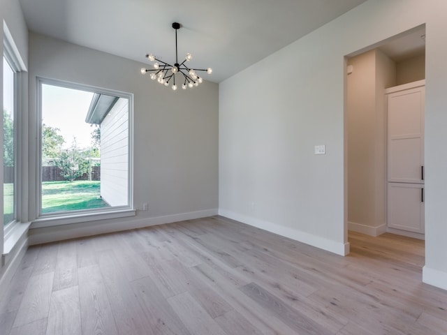 empty room featuring light hardwood / wood-style flooring and a chandelier