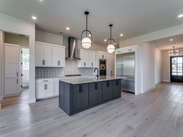 kitchen with built in appliances, wall chimney exhaust hood, light wood-type flooring, and white cabinets