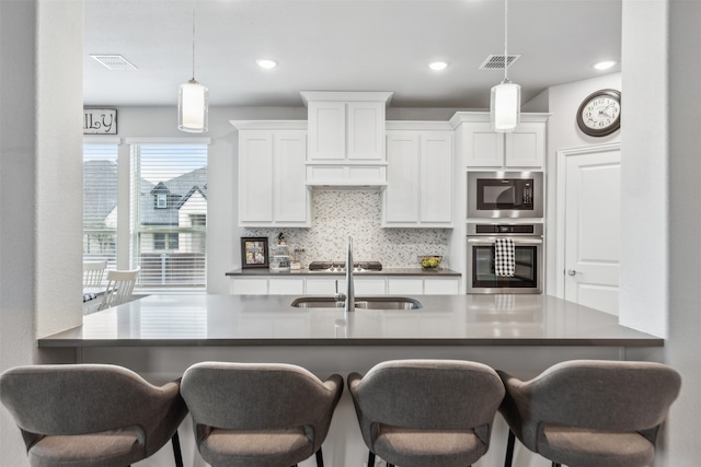 kitchen with backsplash, pendant lighting, a breakfast bar area, and appliances with stainless steel finishes