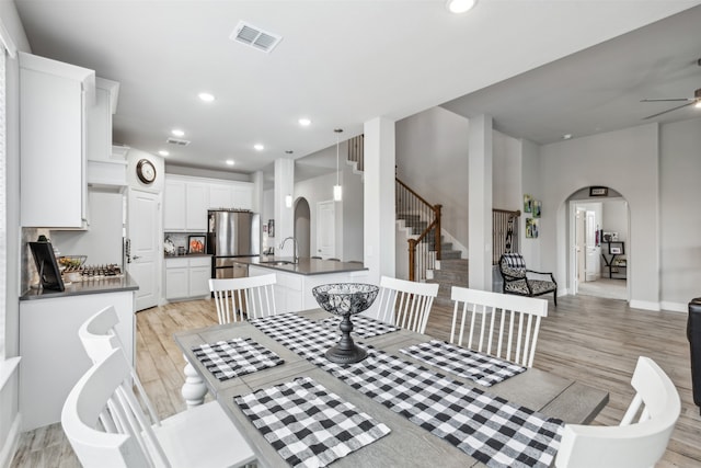 dining area with a high ceiling, sink, ceiling fan, and light hardwood / wood-style floors