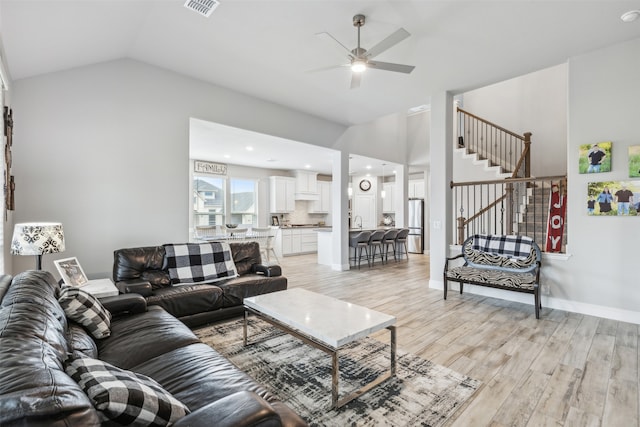 living room featuring lofted ceiling, ceiling fan, and light hardwood / wood-style flooring