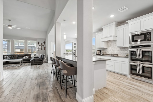 kitchen with white cabinets, plenty of natural light, light hardwood / wood-style flooring, and ceiling fan