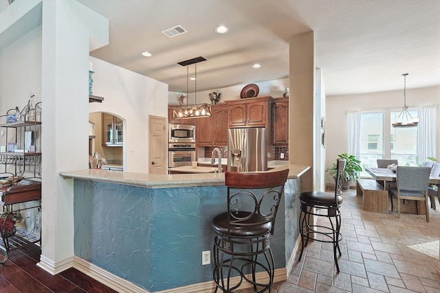 kitchen featuring a breakfast bar, kitchen peninsula, appliances with stainless steel finishes, and a chandelier