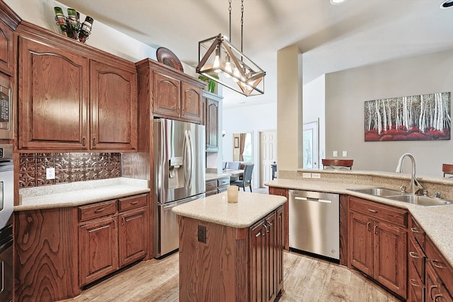 kitchen with a kitchen island, light hardwood / wood-style flooring, hanging light fixtures, stainless steel appliances, and sink