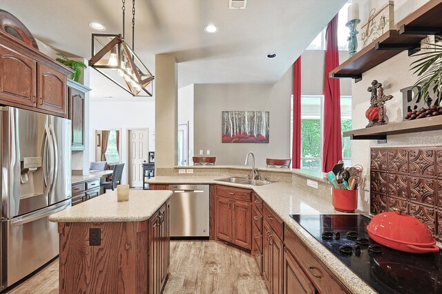 kitchen with sink, a center island, hanging light fixtures, appliances with stainless steel finishes, and light hardwood / wood-style floors