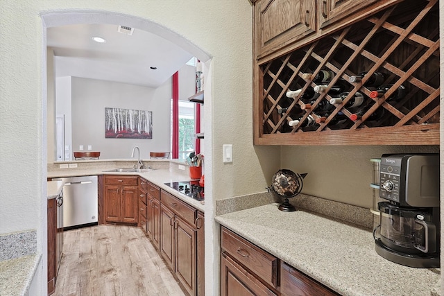 kitchen with light hardwood / wood-style flooring, dishwasher, sink, light stone countertops, and black electric cooktop