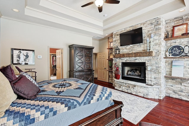 bedroom featuring dark wood-type flooring, ceiling fan, a fireplace, and ornamental molding