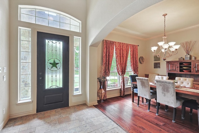 foyer entrance featuring ornamental molding, a notable chandelier, and wood-type flooring