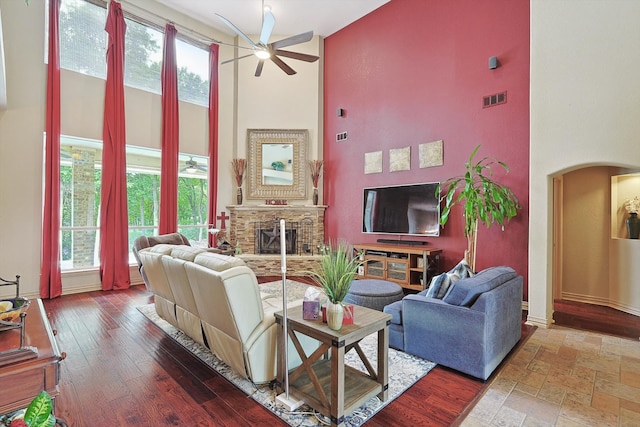 living room with a wealth of natural light, a high ceiling, hardwood / wood-style flooring, and ceiling fan