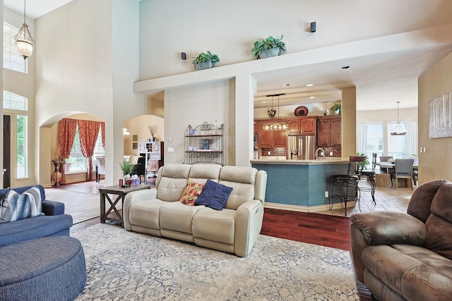 living room with light wood-type flooring and a towering ceiling