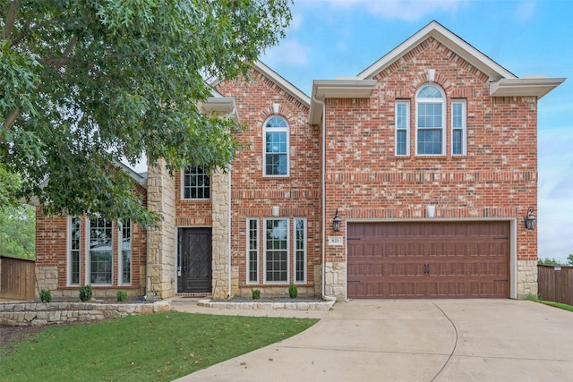 traditional home with driveway, a garage, stone siding, fence, and brick siding