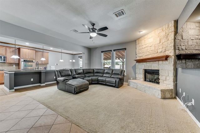 carpeted living room featuring ceiling fan, a fireplace, sink, and a textured ceiling