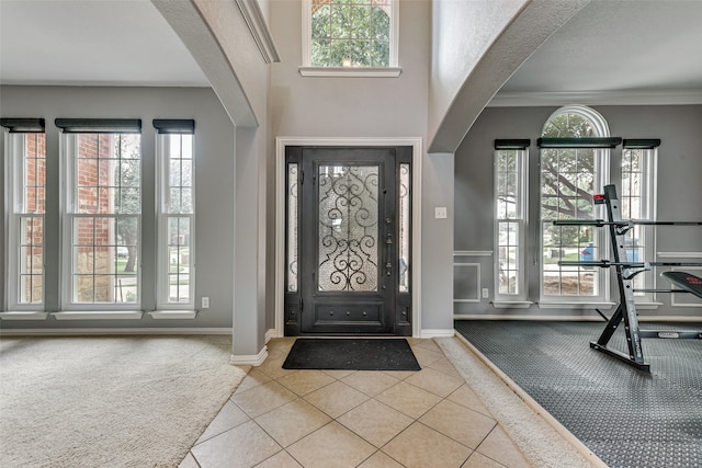 entryway with crown molding and light tile patterned floors