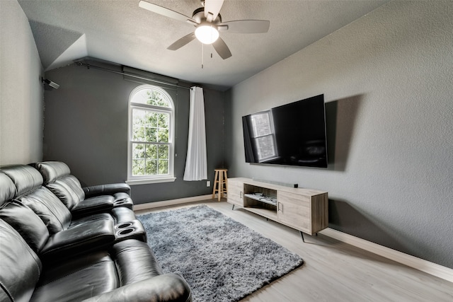 living room with a textured ceiling, ceiling fan, and light hardwood / wood-style floors