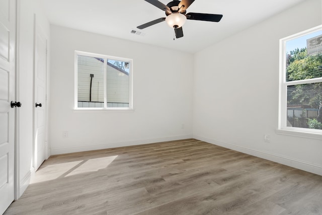 empty room featuring light wood-type flooring, ceiling fan, and a wealth of natural light