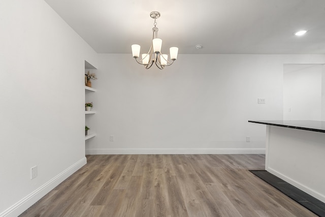 unfurnished dining area with a chandelier and light hardwood / wood-style floors