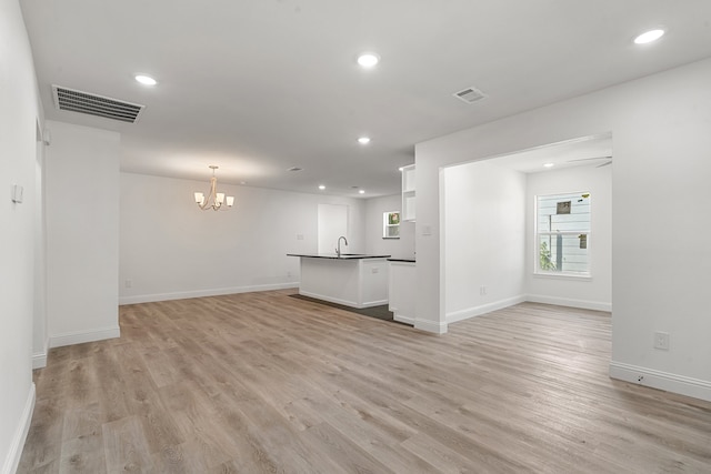 unfurnished living room featuring a chandelier, sink, and light hardwood / wood-style flooring