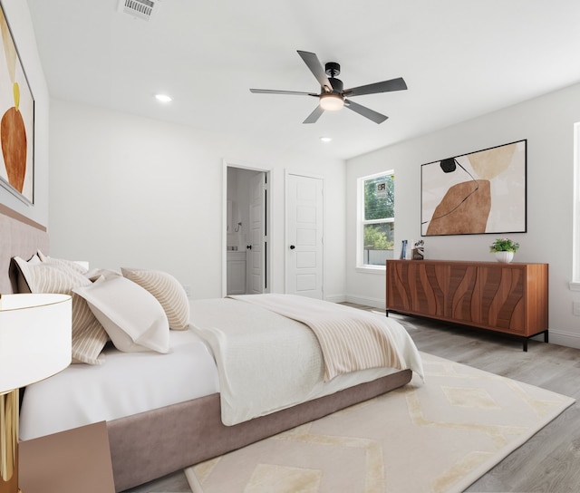 bedroom featuring light hardwood / wood-style flooring, ceiling fan, and ensuite bath