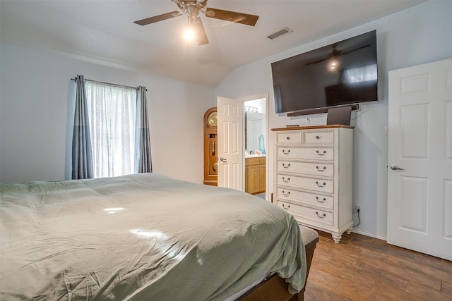 bedroom with hardwood / wood-style floors, connected bathroom, vaulted ceiling, and ceiling fan